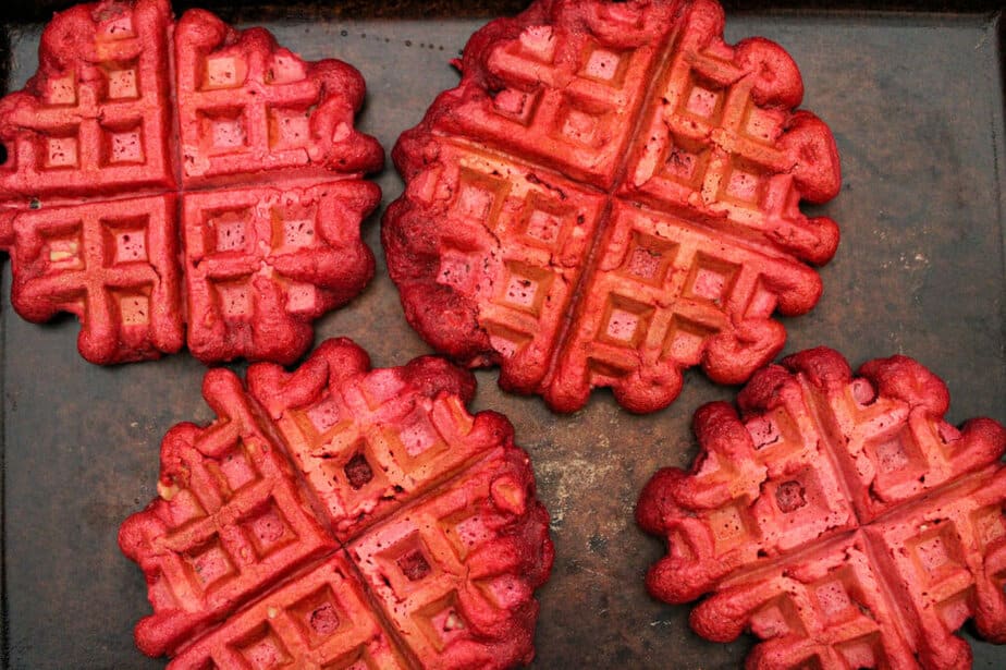 Cooked, vibrantly red, beet waffles on a platter.