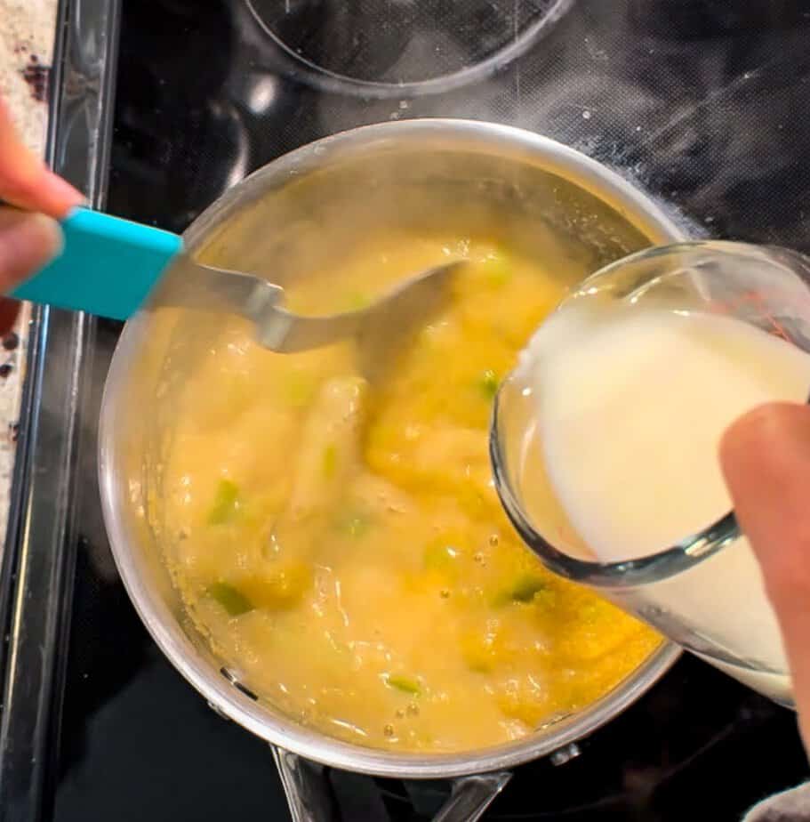 Milk added to polenta mixture in pot.