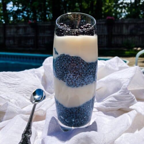 Layered pudding with white cream and blue chia pudding in a dessert glass.