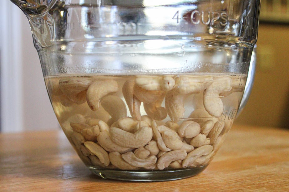 Cashews soaking in water in a clear glass bowl