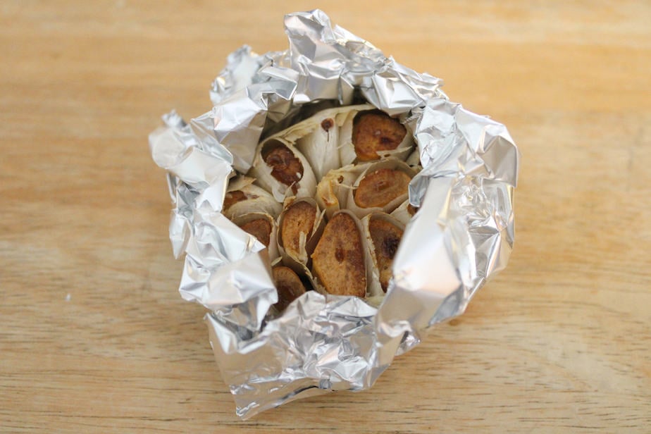 Roasted garlic bulb wrapped in aluminum foil.