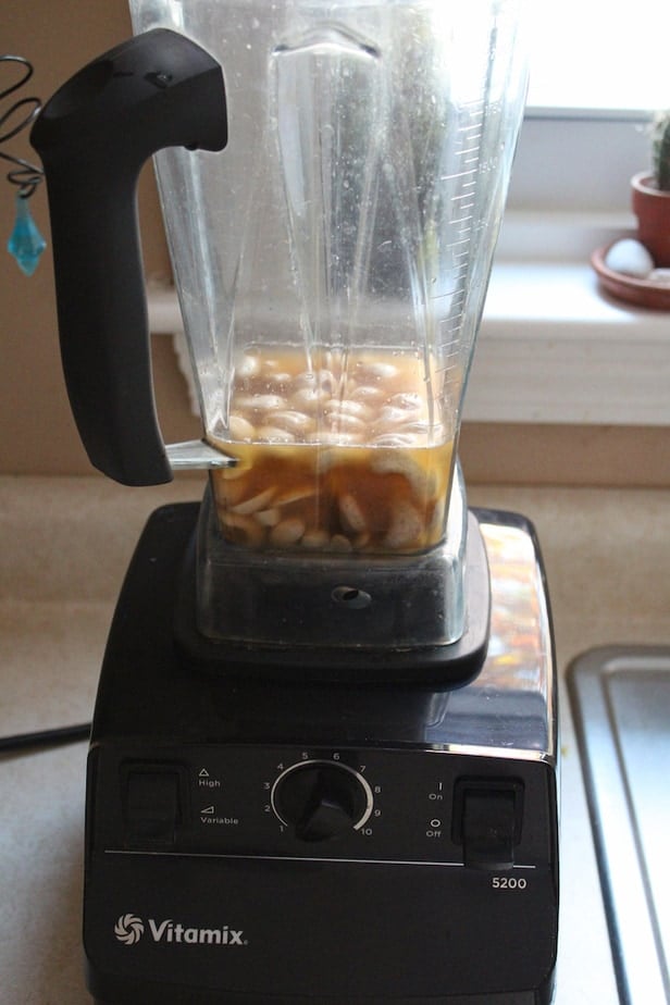 Cashews and ingredients in a blender that are yet blended.