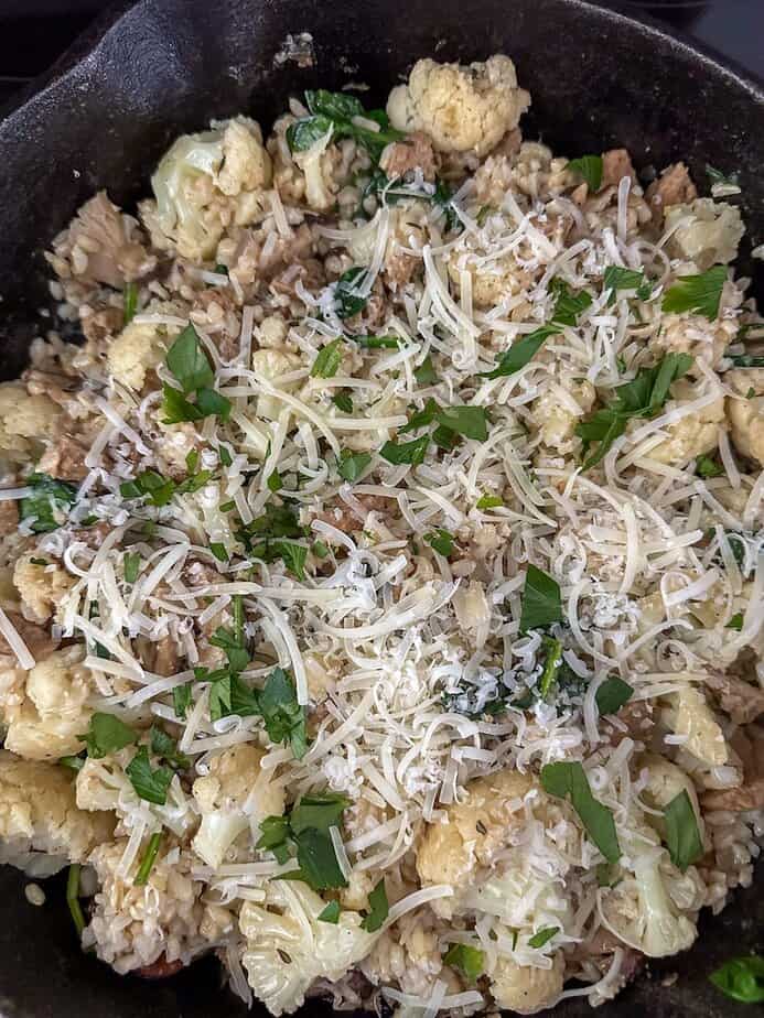 Shredded cheese and fresh herbs added to cauliflower skillet.
