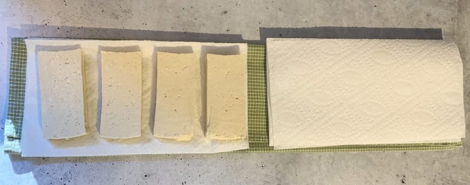 Slices of tofu on one side of folded towels.