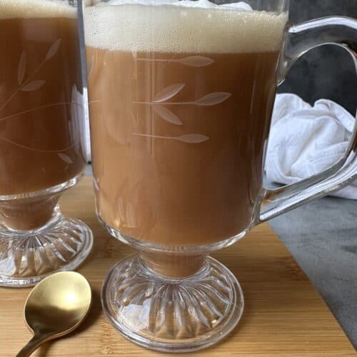 Royal breakfast tea latte in a clear glass mug with milk foam on top.