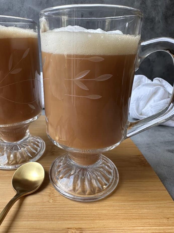 Royal breakfast tea latte in a clear glass mug with milk foam on top.