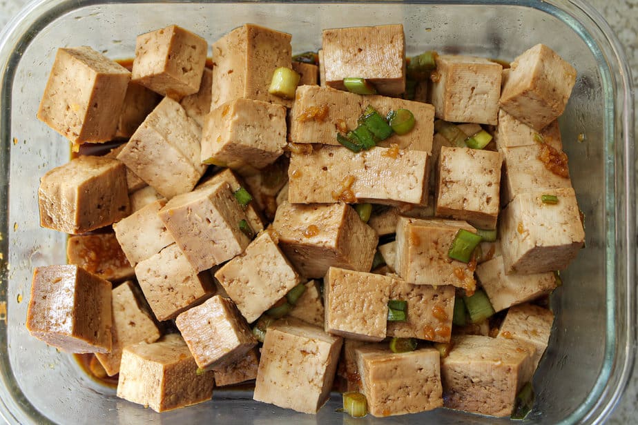 Cubed tofu that is marinating in a clear glass dish.