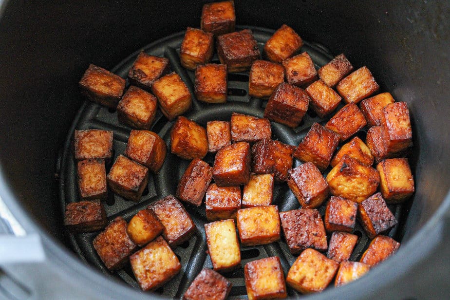 Crispy air fried tofu in a air fryer basket. 