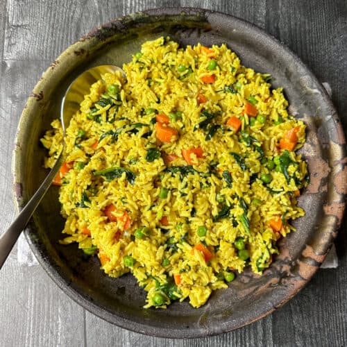 Curried rice in a dark ceramic bowl.