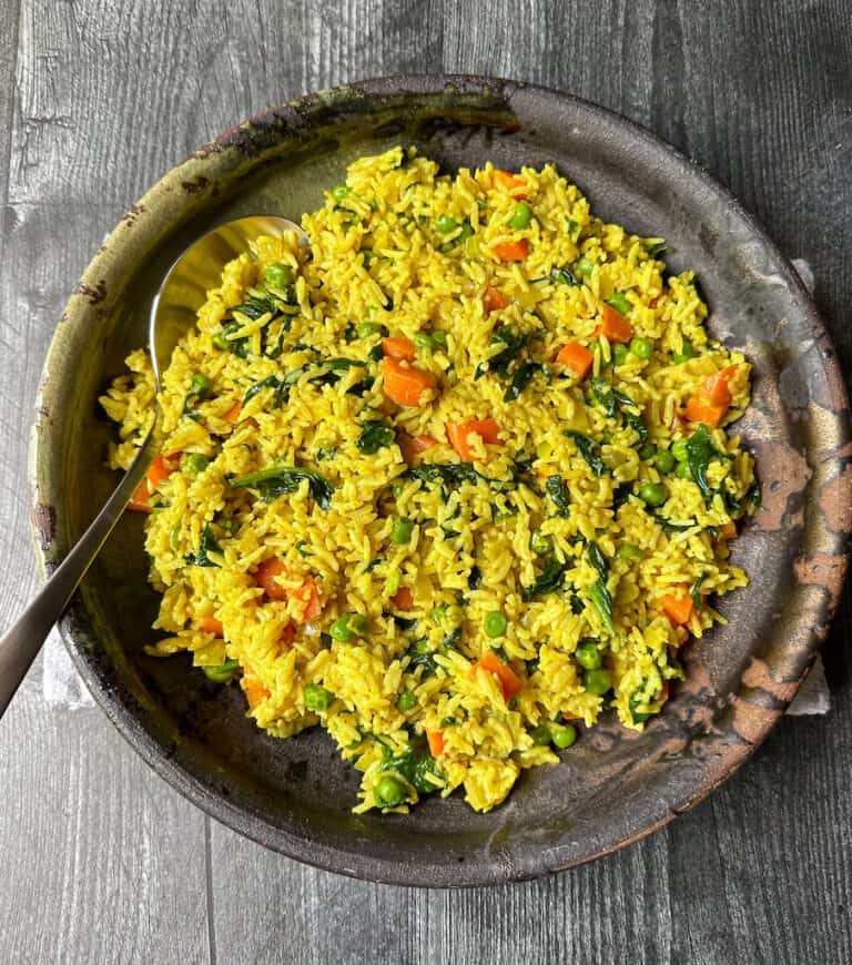 Curried rice in a dark ceramic bowl.