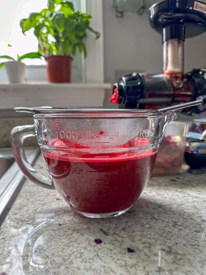 Beet and carrot juice that has been strained in a clear glass bowl.