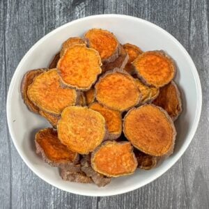 Dehydrated sweet potato dog treats in a white bowl.