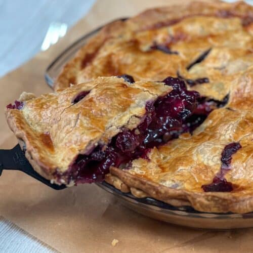 Baked blueberry pie with slice of pie lifting out of dish.