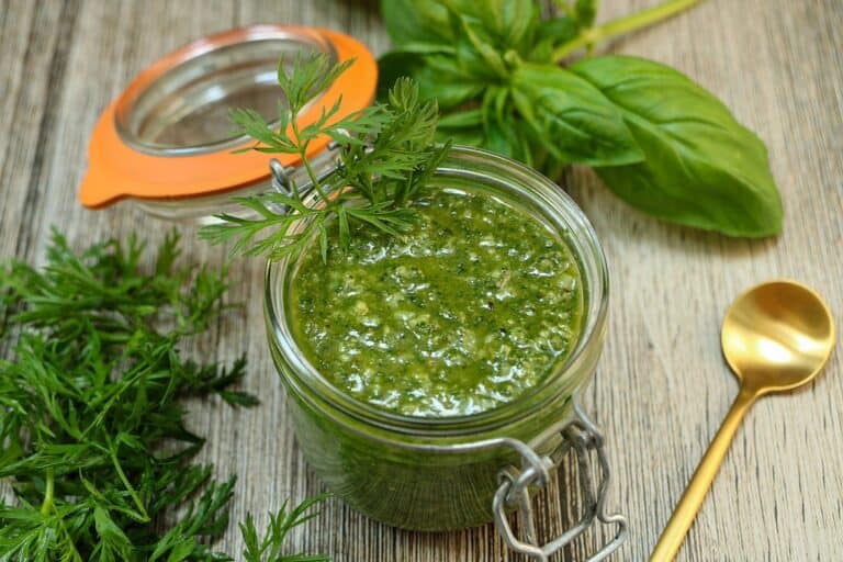 Glass jar filled with green carrot top pesto.