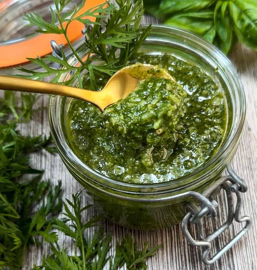 Gold spoon dipping out of a jar of Carrot Top Pesto.