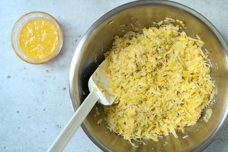 Small bowl with beaten eggs and larger bowl with summer squash mixture.