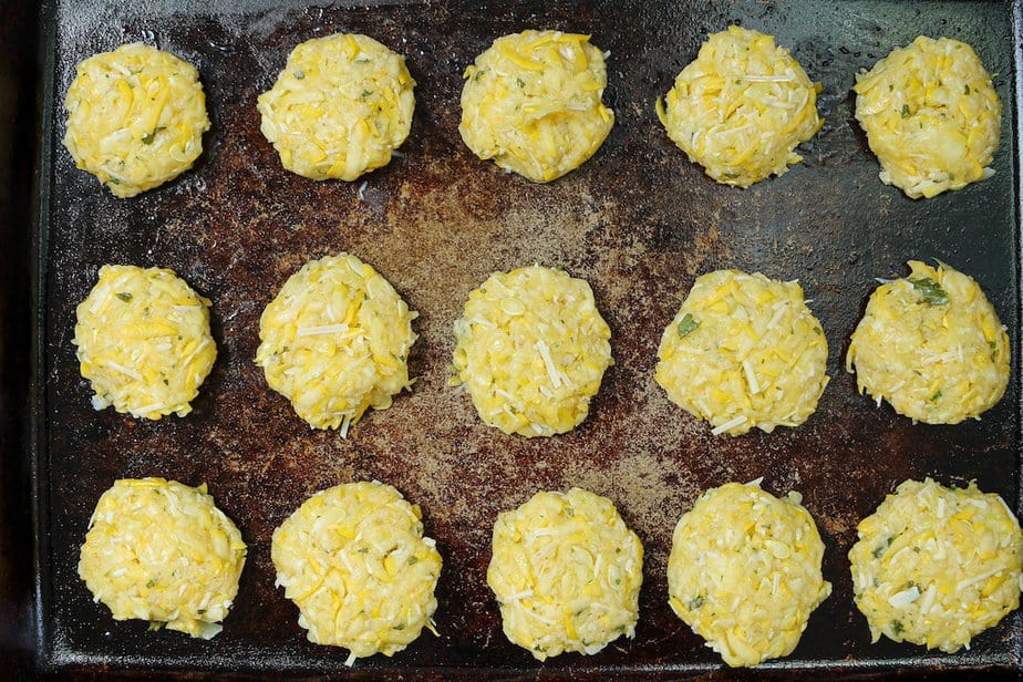 Uncooked summer squash rounds on a baking sheet.