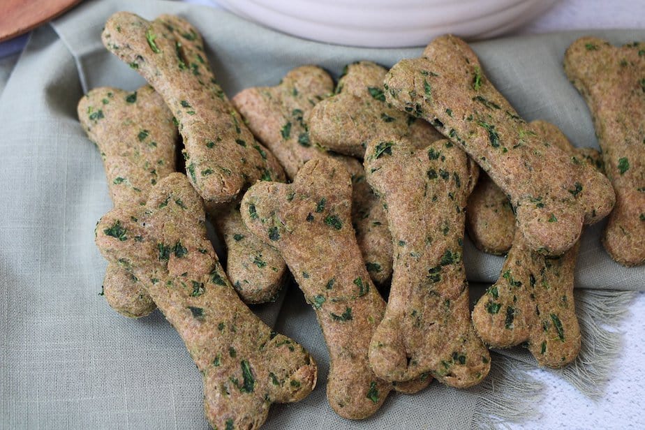 Homemade dog cookies that have kale incorporated into the treat and are in dog-bone shapes.