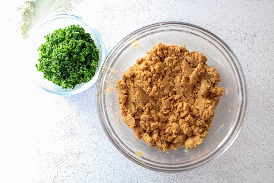 Two clear glass bowls; one with dog cookie batter and the other with minced green kale.
