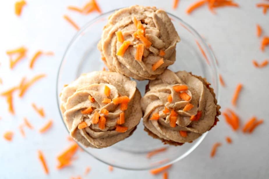 Three frosted pupcakes on a clear glass plate.