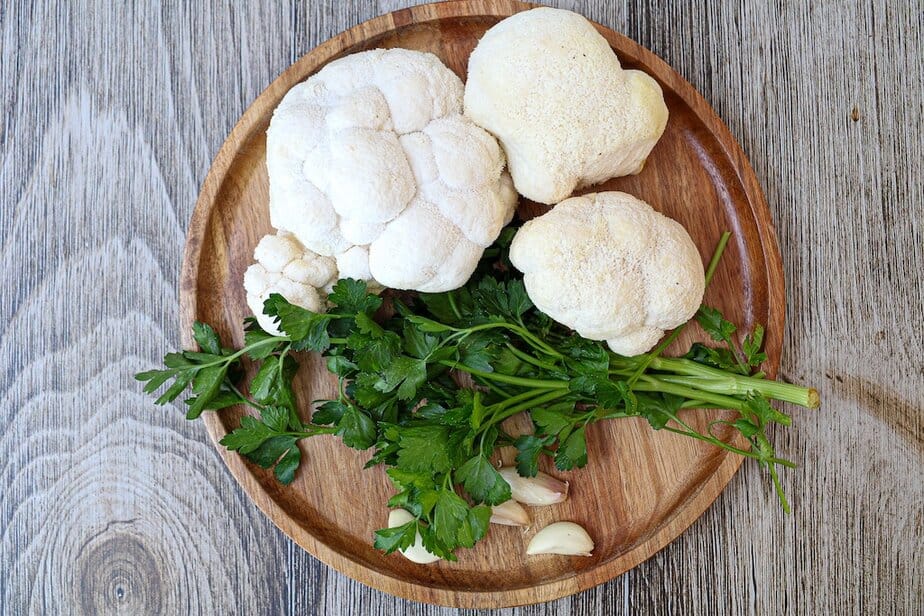 Wooden plate with Lion's Mane mushrooms, parsley and garlic cloves.