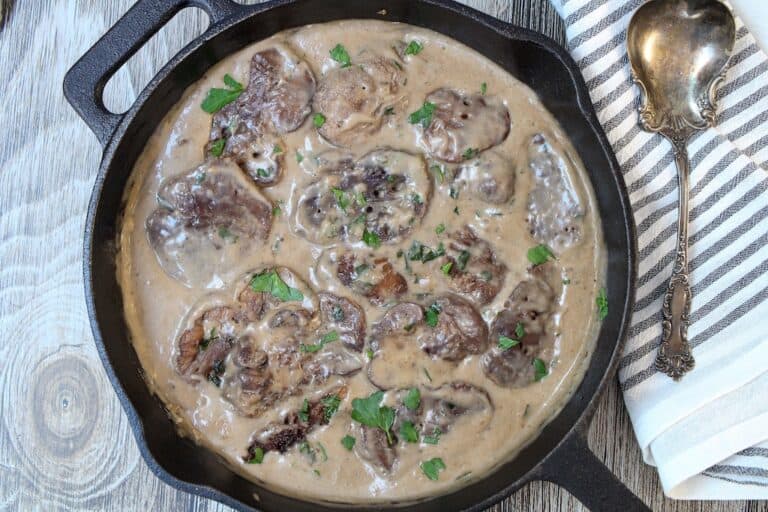 Lion's Mane Mushroom Steaks in gravy in a cast iron pan.