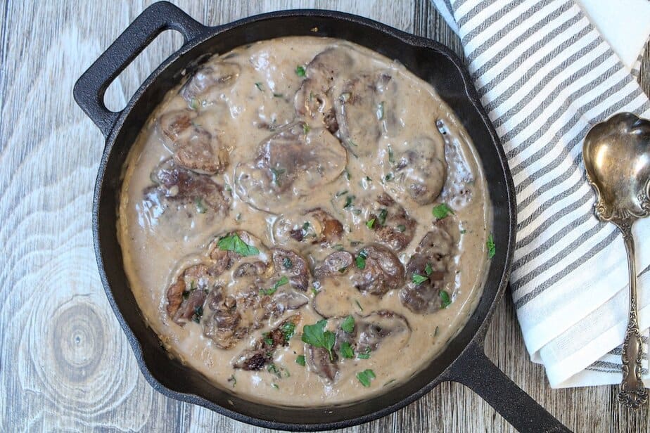 Lion's Mane Mushroom Steaks in a creamy gravy in a cast iron pan.