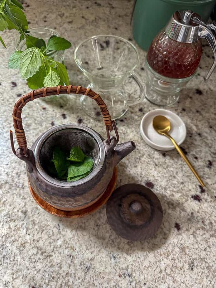 Tea pot with lemon balm leaves in the pot.