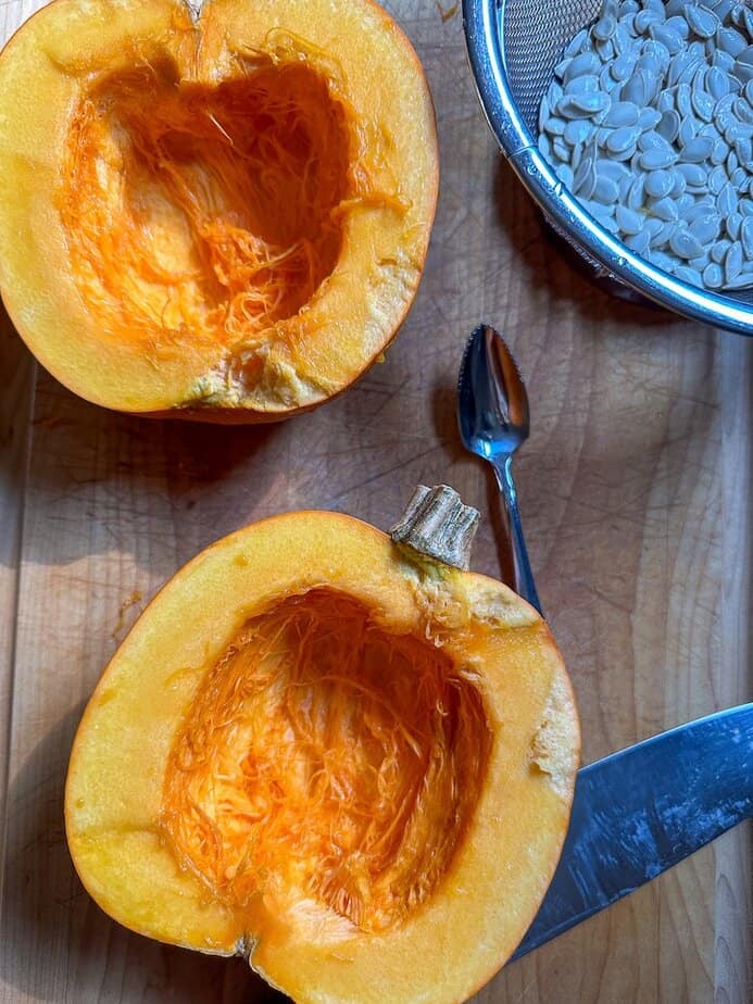 Whole pumpkin cut in half with seeds removed.