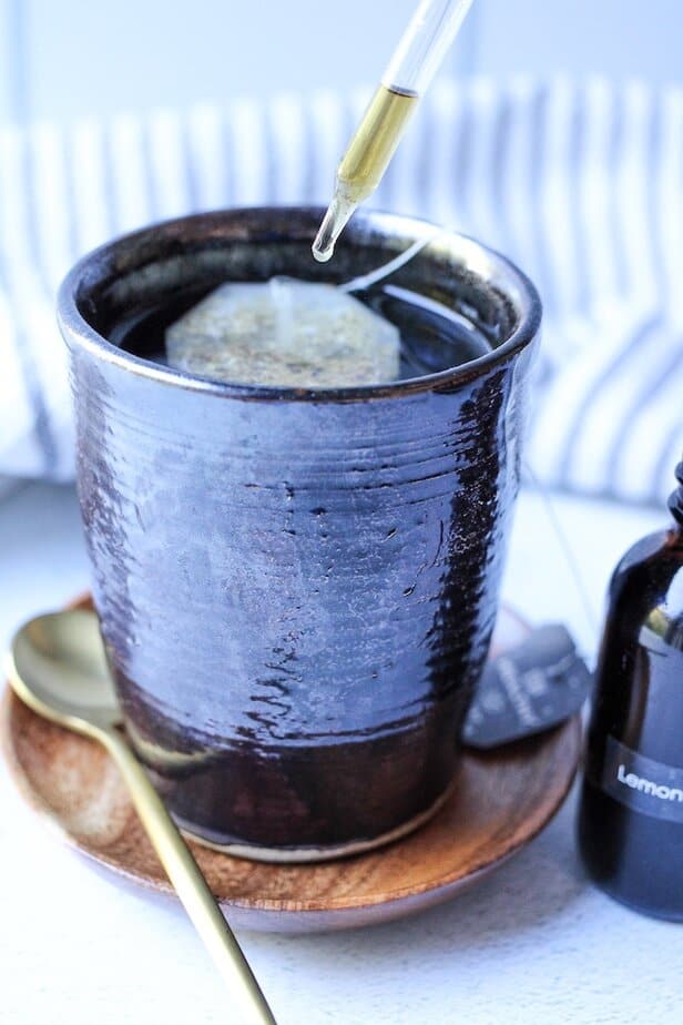 Drop of lemon balm extract being added to a cup of tea.