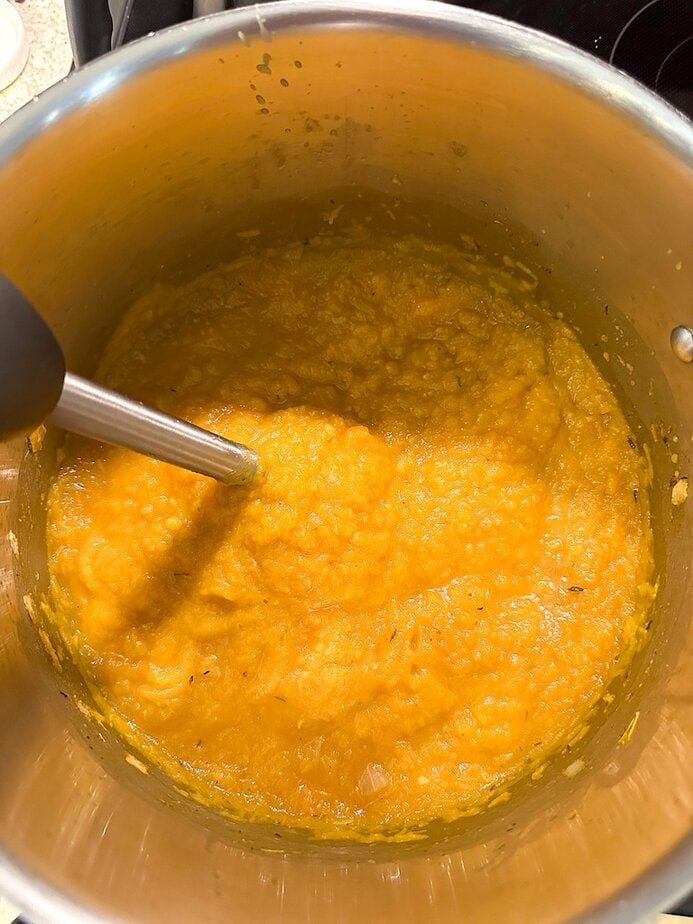 Immersion blender blending pumpkin soup.
