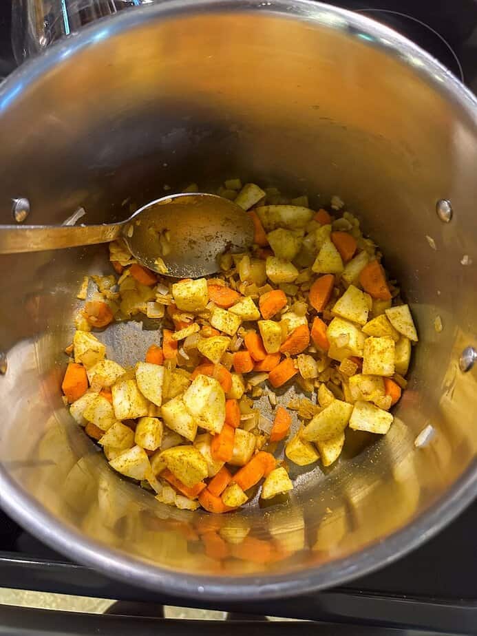 Vegetables and spices sautéing in large pot.