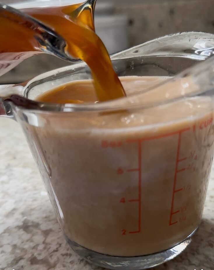 Chai syrup added to measuring cup.