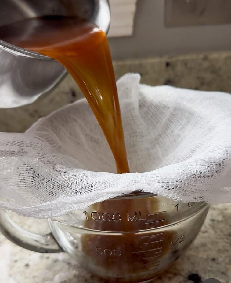 Chai latte syrup being strained through a cheesecloth. 