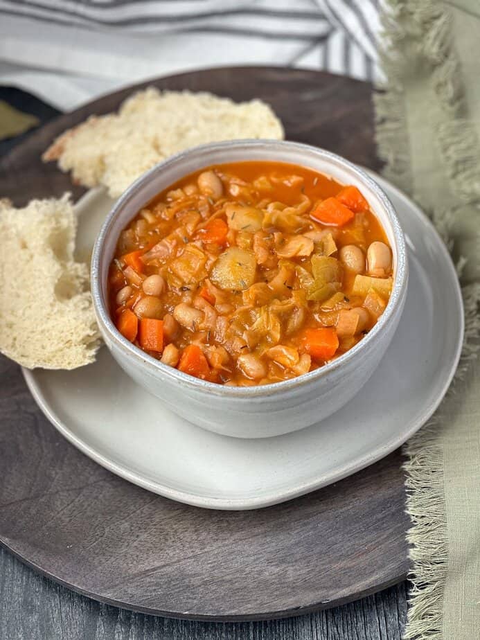 Irish vegetarian stew in a ceramic bowl with bread on the side.