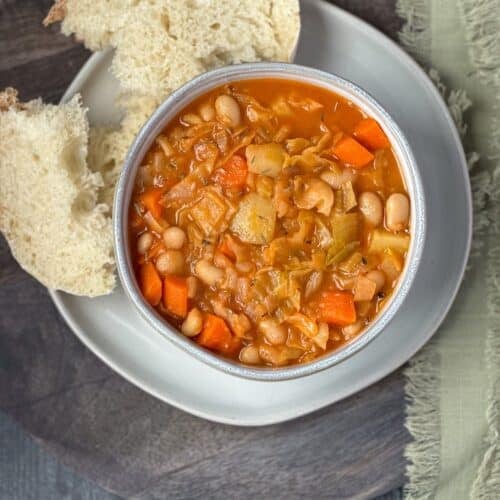 Irish vegetarian stew in a ceramic bowl with bread on the side.