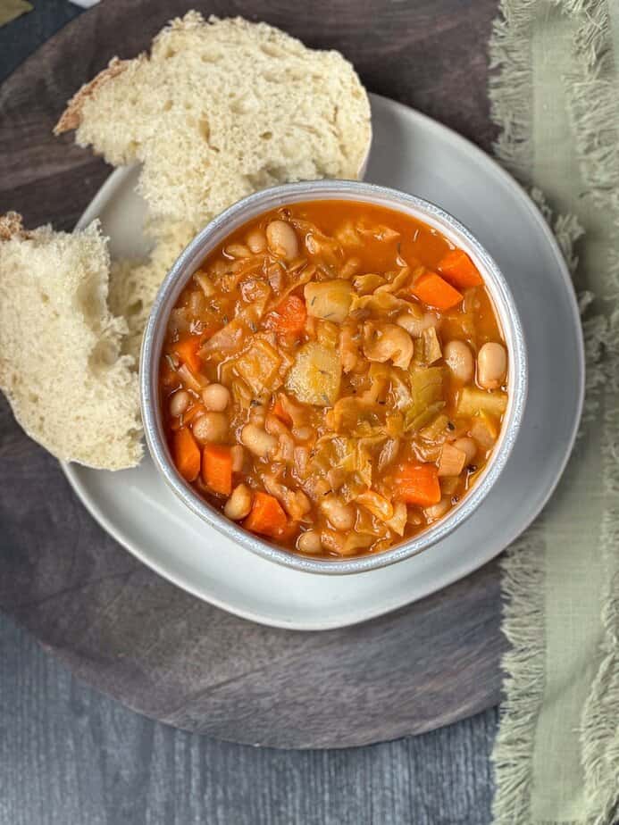 Irish vegetarian stew in a ceramic bowl with bread on the side.