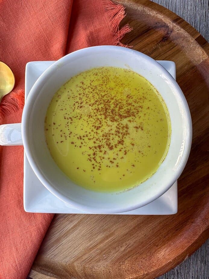 Turmeric latte in a white ceramic cup with cinnamon sprinkled on top.