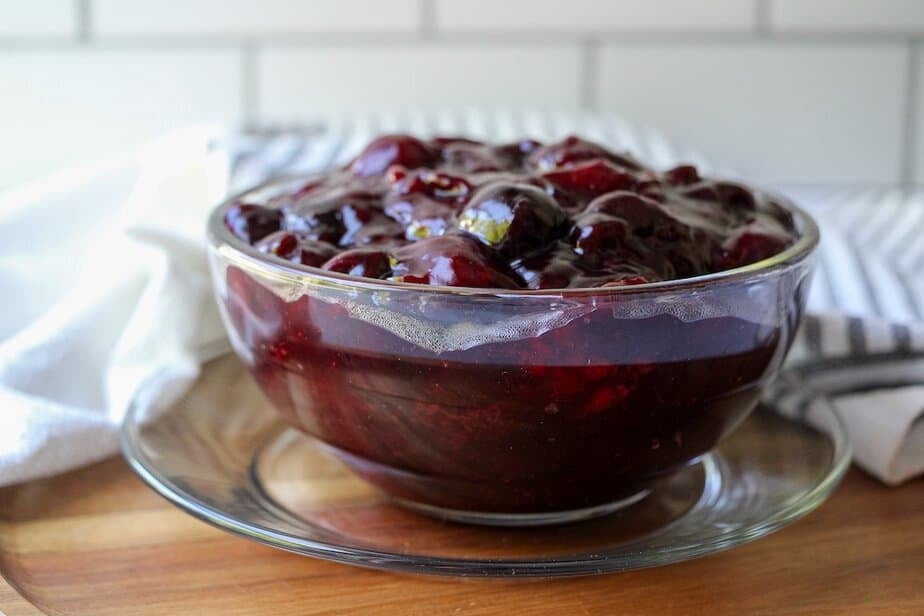 Side view of cherry pie filling in a clear glass bowl.
