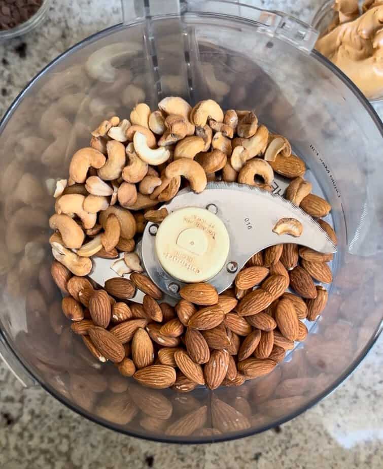 Almonds and cashews in food processor bowl.