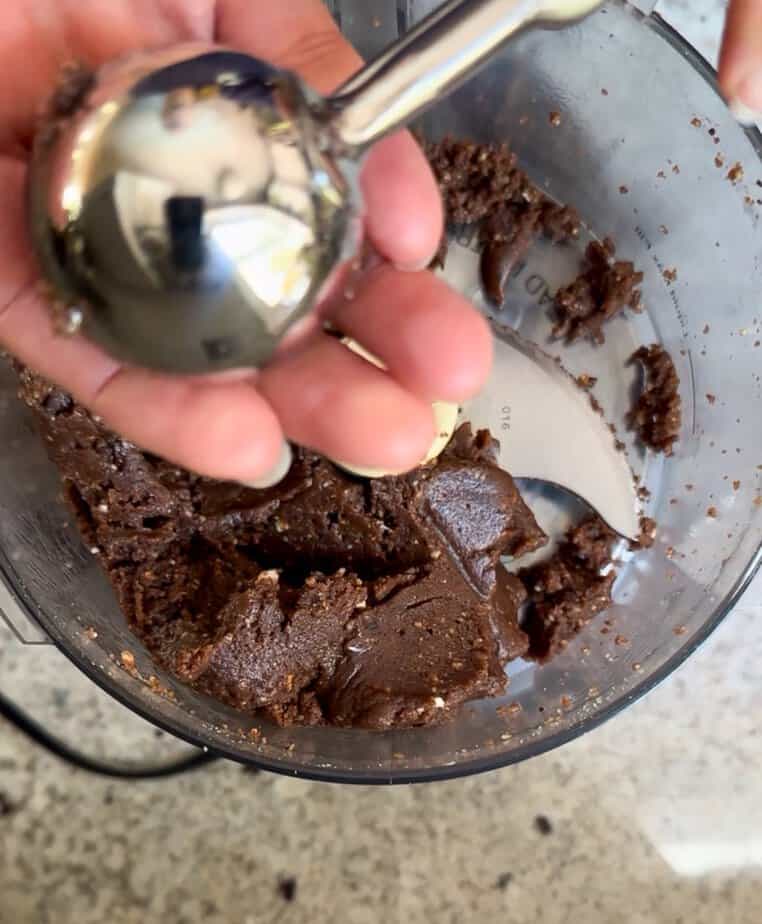 Scoop adding dough to hand.