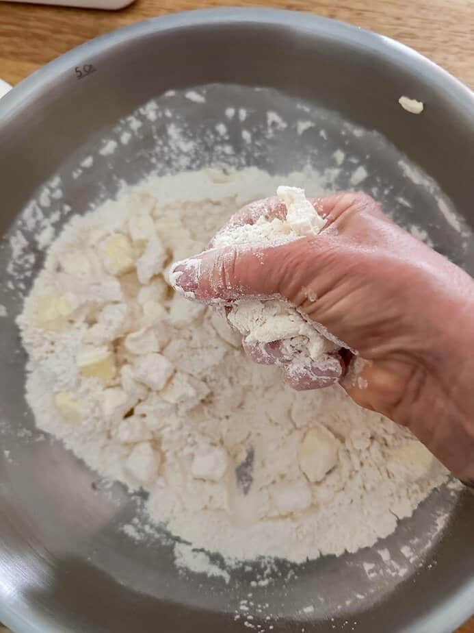 Hand incorporating butter into the flour.