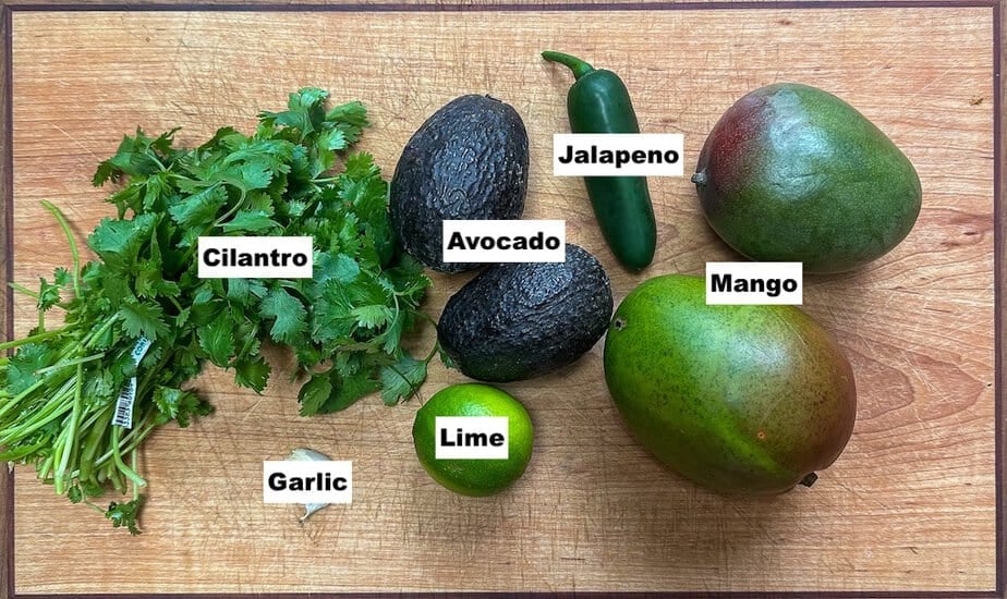 Ingredients for salsa, pictured are two avocado's, two mango's, one lime, one jalapeño, and a bunch of cilantro.