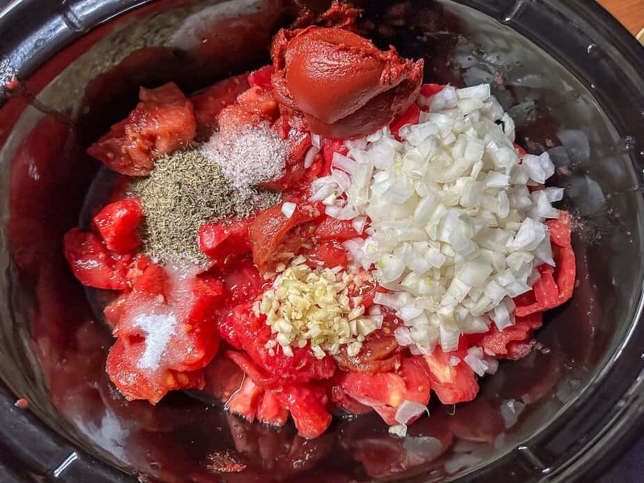 Ingredients for slow cooker fresh tomato spaghetti sauce in the base of the slow cooker.