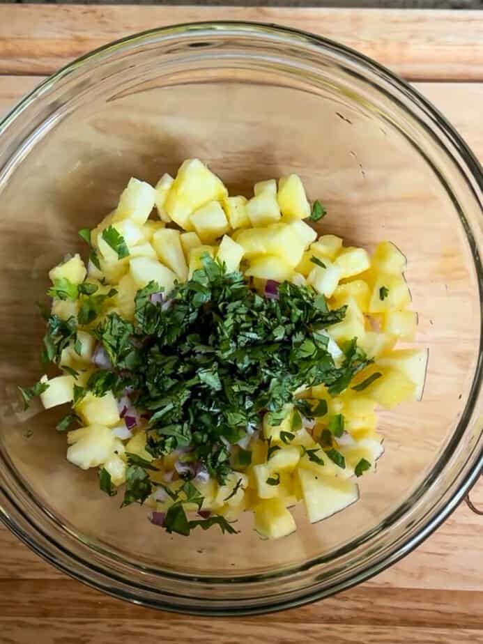 Ingredients for fresh pineapple salsa added to a mixing bowl.
