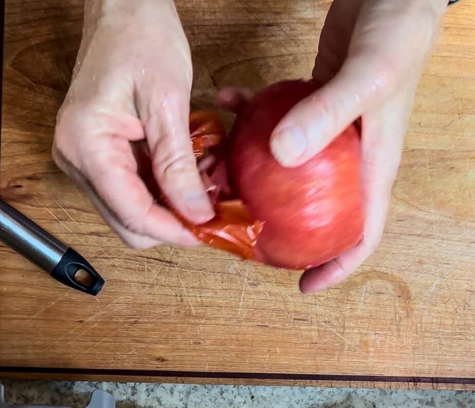 Hand peeling skin off of a tomato.