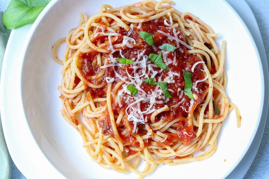Slow cooker spaghetti sauce with fresh tomatoes over spaghetti noodles on a plate.