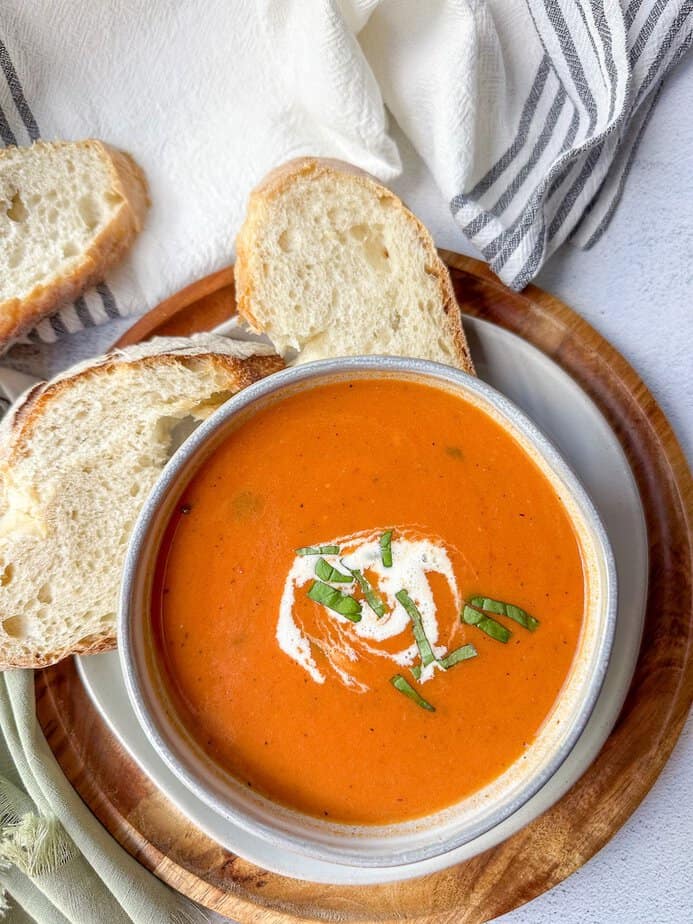 Crockpot tomato soup in a bowl with fresh bread around the base of the bowl.