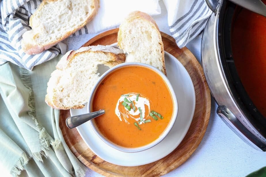 Crockpot tomato soup in a bowl with fresh bread on the side.