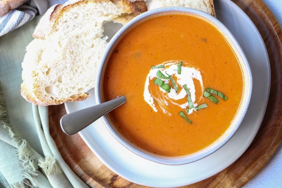 Creamy tomato soup in a bowl with fresh bread on the side.